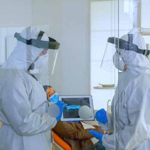 dentist-doctors-overall-using-tablet-explaining-dental-x-ray-stomatologic-office-coronavirus-man-wearing-face-shield-mask-showing-nusrse-radiography-using-digital-device_482257-3541